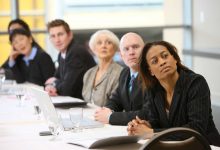 Businesspeople watch presentation in board room