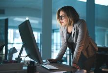 Woman, employee and reading on computer in office on browsing internet, online and research for ideas. Female person, workplace and desk with deadline or overtime, project and standing as hr