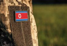 Close up millitary woman or man shoulder arm sleeve with North Korea flag patch. Troops army, soldier camouflage uniform. Armed Forces, empty copy space for text