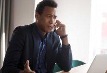 Angry stressed black male businessman disputing on phone with partner. Outraged african american manager, lawyer, banker, consultant or real estate agent listening bad news from client at office.