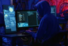 Hackers in dark room running code to breach defenses and exploit weaknesses in computer systems. Evil developers in basement getting past companies security networks, handheld camera shot