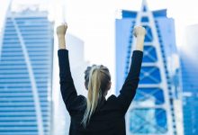 Business success - Celebrating businesswoman overlooking the city center high-rises.