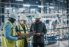 Young Diverse Team of Car Factory Specialists Working on Laptop and Tablet Computers. Engineers Discussing Automotive Industrial Manufacturing Technology on Modern Vehicle Assembly Plant.