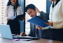 Laptop, stress and business people with planning, man and accounting with research for stock market. Employees, time management and leader with documents, pressure and multitasking in Japan